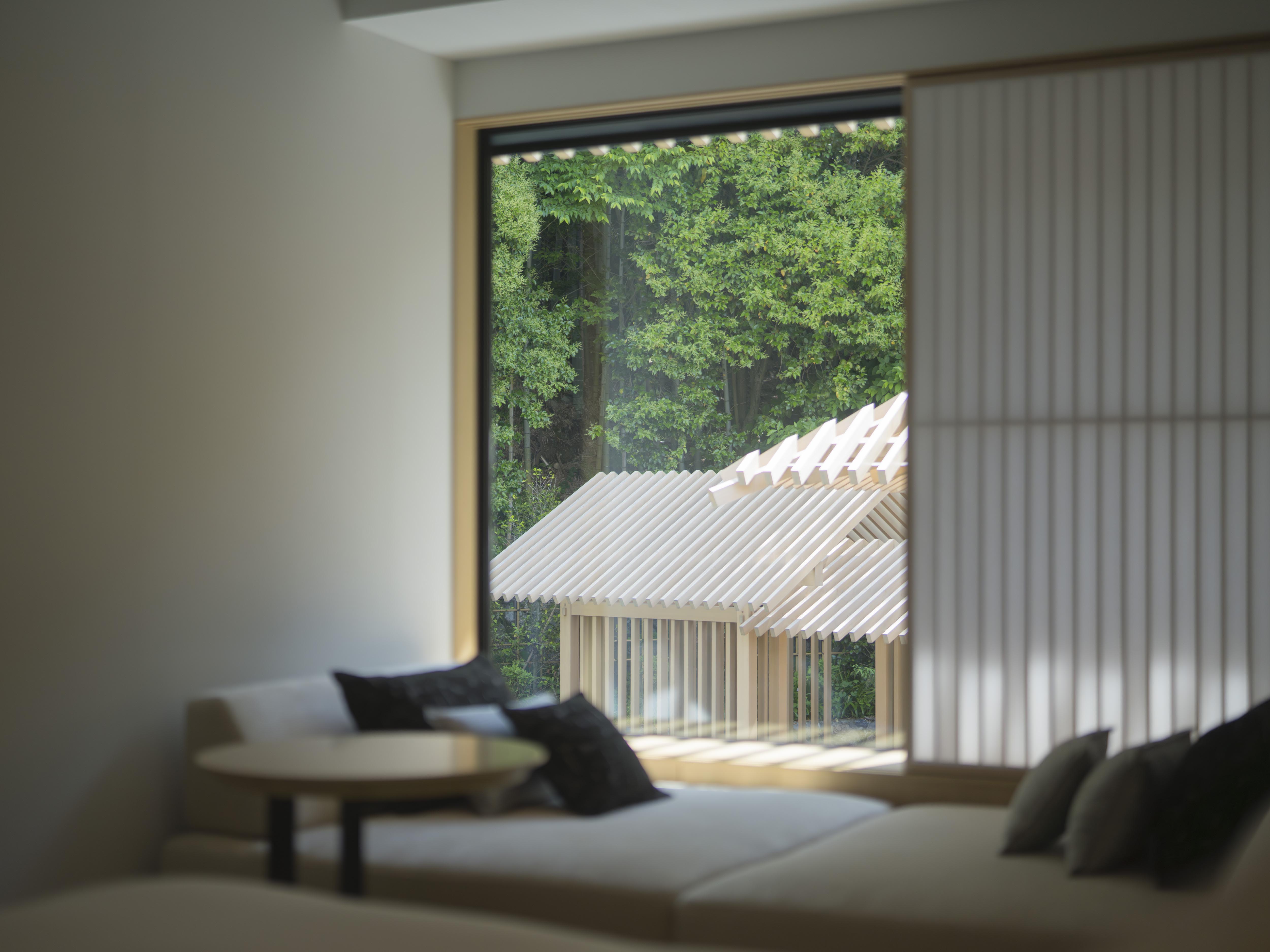 Room overlooks garden with large window, featuring plush seating at Banyan Tree Higashiyama Kyoto.